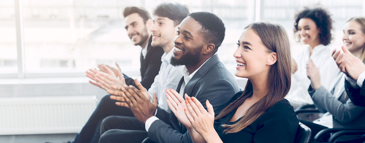 People in a business audience setting, clapping