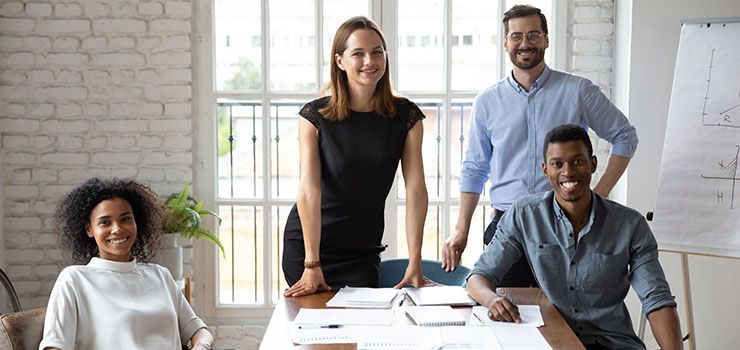 3 people smiling whilst at their desk