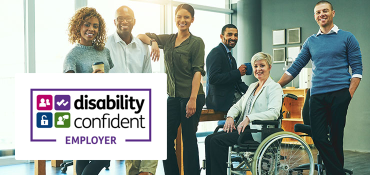 A group of people smiling at work, with the Disability Confident Employer logo showing