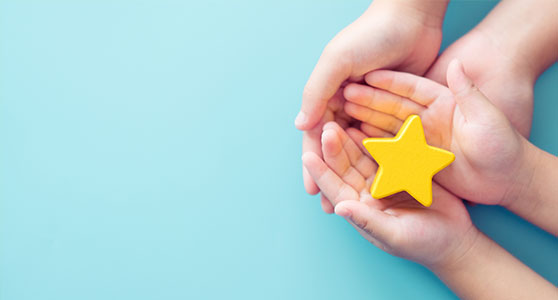 Two pairs of hands holding a star shaped object